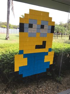 a lego character made to look like a minion sitting in the middle of a yard