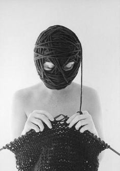 a woman wearing a mask and holding a piece of yarn