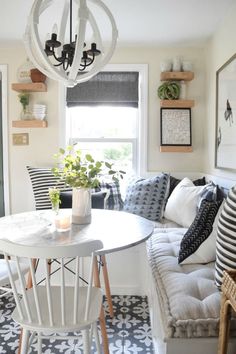 a white table and chairs in a room with black and white floor tiles on the walls