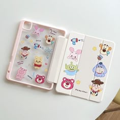 three cell phones with cartoon stickers on them sitting next to each other, one is pink and the other is white