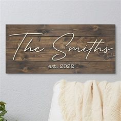 a wooden sign that says the smiths and is hanging on a wall next to a bed