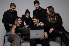 a group of people sitting on top of a couch next to each other using laptop computers