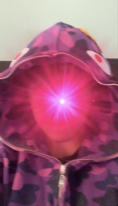 a person wearing a purple hoodie with a pink light shining through it's center