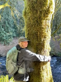 a man standing next to a tree covered in moss