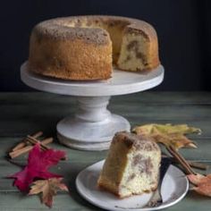 a bundt cake on a white plate with a slice cut out and autumn leaves around it