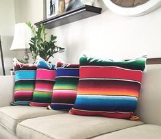 three multicolored striped pillows sitting on a white couch in front of a mirror