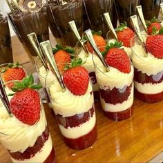 desserts with strawberries are arranged on a wooden table and lined up in rows