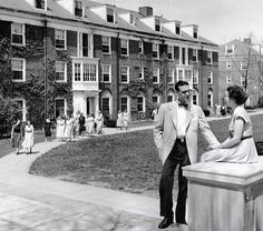 a man and woman standing next to each other in front of a building