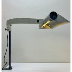 a desk lamp that is on top of a white surface with the light turned on