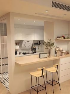 two stools are sitting at the bar in this modern style kitchen with white cabinets and counters