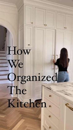 a woman is standing in the kitchen with her hand on the door handle and looking at the cabinets