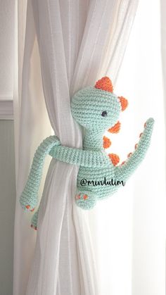 a crocheted stuffed animal hanging from the side of a window curtain with white drapes