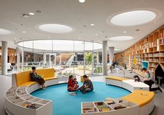 children are sitting on the floor in a circular room with bookshelves and tables