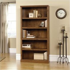 a wooden book shelf with books on it and a clock in the corner behind it