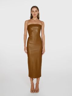 a woman wearing a brown leather dress with strapless shoulders and high slited heels