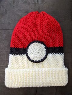 a red and white knitted hat with a pokeball on it's side