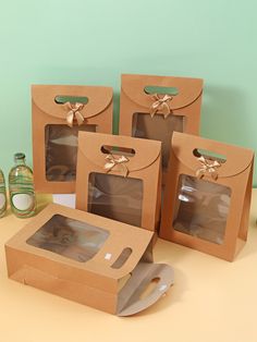 four brown boxes with bows on them sitting on a table next to bottles and glasses