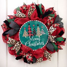 a christmas wreath with leopard print and red, black and green bows hanging on a white door