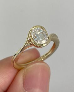 a hand holding a yellow gold ring with a white diamond