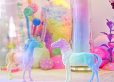 two toy horses standing next to each other in front of some candy balls and candles