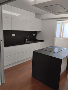 an empty kitchen with white cabinets and black counter tops, along with wood flooring