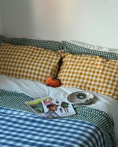 a bed with gingham checkered sheets and pillows on it, next to an orange ball