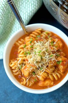 a white bowl filled with pasta and sauce next to an instant pressure cooker in the background