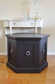 a black corner table with drawers on the top and two white tables in the background