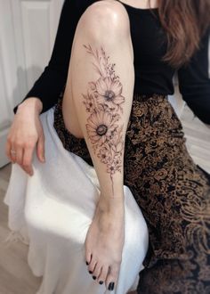 a woman sitting on top of a bed next to a white sheet with flowers on it