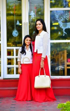 two women standing in front of a store with their arms around each other, both wearing red skirts