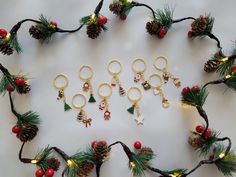 christmas decorations and pine cones are arranged on a white surface with red berries, pine cones, and gold bells