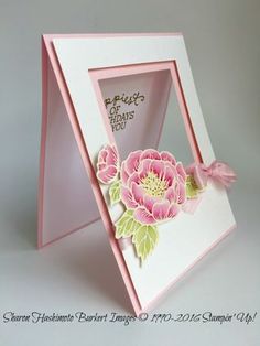 a pink and white card with a flower in the center, inside an open box