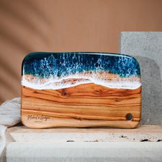 a wooden tray with waves on it sitting on top of a table next to a concrete block