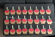 an arrangement of apple shaped cookies with toothpicks in them sitting on a table