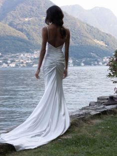 a woman in a wedding dress looking out over the water