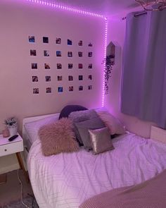 a bedroom with purple lights and pillows on the bed, along with pictures on the wall