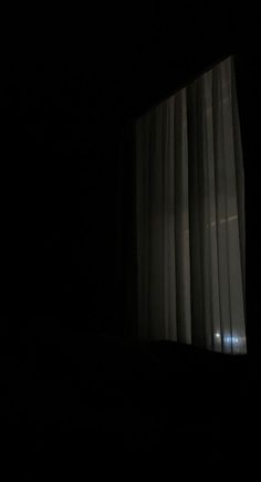 an open window with curtains in the dark