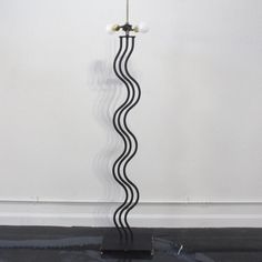 a black and white floor lamp with three balls on it's base in front of a wall