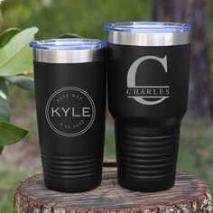 two personalized tumblers sitting on top of a tree stump