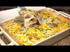 a casserole dish with meat and cheese being scooped from the casserole