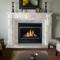 a living room with a fire place in the center and two chairs around the fireplace