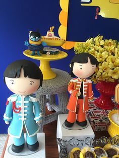 two toy figurines are standing on pedestals in front of some desserts