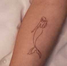 a woman's arm with a tattoo of a mermaid holding a ballon d'or