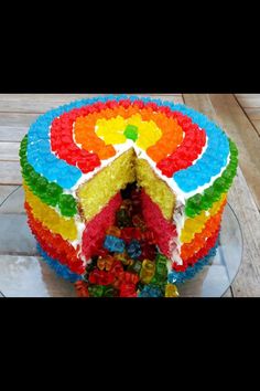 a multi colored cake with lots of gummy bears on it's side and one slice taken out