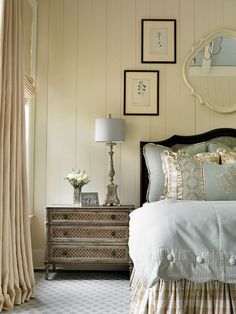 a white bed sitting under a mirror next to a dresser with drawers and lamps on top of it