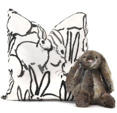 a stuffed rabbit sitting next to a pillow on a white background with black and white designs