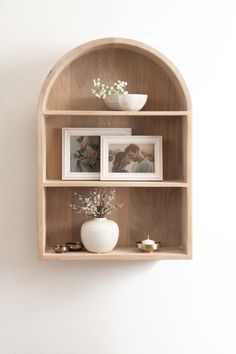 a wooden shelf with pictures and flowers on it