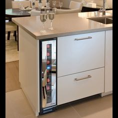 a refrigerator with two wine glasses on top of it in the middle of a kitchen