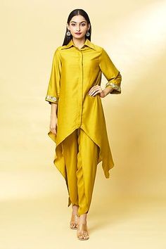 Mustard tunic with embroidery on the sleeve hems and spread collar. Comes with draped pants.
Component: 2
Pattern: Embroidery
Type Of Work: Sequin
Neckline: Spread Collar
Sleeve Type: Three Quarter
Fabric: Cotton Silk
Color: Yellow
Other Details: 
Asymmetrical hem
Pant with draped layer in front
Closure: Concealed button front
Occasion: Sangeet - Aza Fashions Draped Pants, Cotton Short Dresses, Western Dresses For Women, Drape Pants, Frock Fashion, Womens Trendy Dresses, Polka Dot Maxi Dresses, Dress Design Patterns, Designer Blouse Patterns