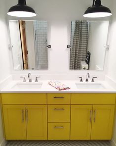 a bathroom with two sinks, mirrors and lights on the wall above them is shown